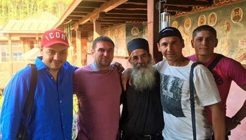 Seyar Kurshutov (in a bright red baseball cap) poses against the backdrop of the Athos monastery where he is visitingGleb Lobov, Vladimir Skorobogach, Vitalia Kopylenko